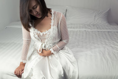 Young woman sitting on bed at home