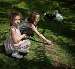 Two girls on grass with ducks 