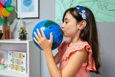 Female student kissing a handmade globe world at ecology classroom