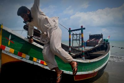 Man on boat in sea against sky