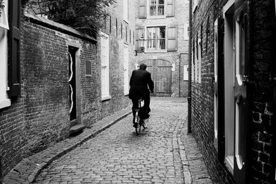 Rear view of man walking on footpath in city