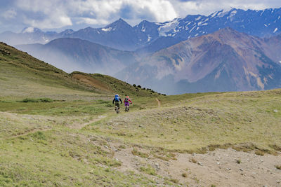 Rear view of two people walking on mountain road