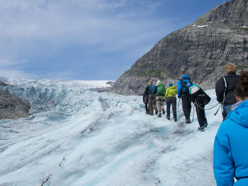 Rear view of people walking on cliff against sky