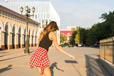 Side view of woman against building in city