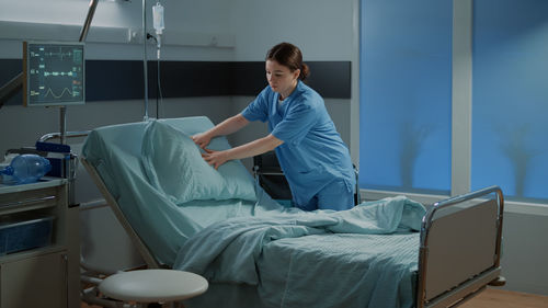 Side view of woman using mobile phone while sitting on bed at home