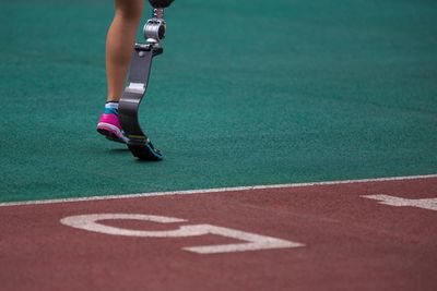 Low section of woman with artificial leg running on track