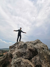 Man standing on rock against sky