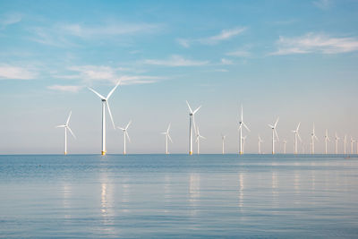 Wind turbines in sea against sky