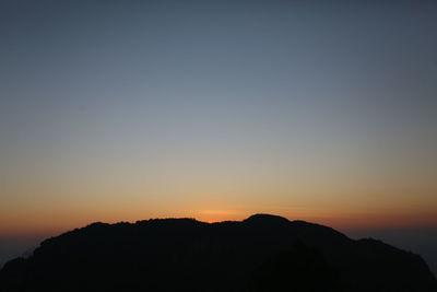 Scenic view of silhouette mountains against clear sky at sunset