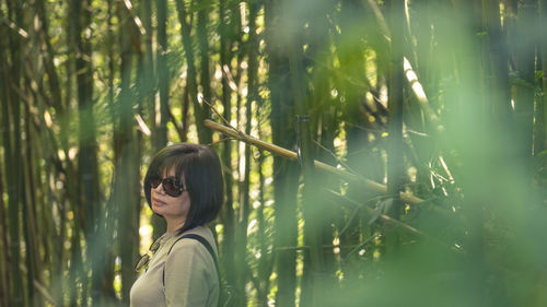 Side view of young woman standing against plants