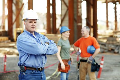 Portrait of male construction foreman with two workers behind