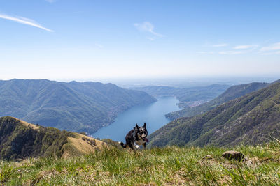 Rear view of man sitting on mountain against sky