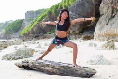 Young woman standing on rock at beach