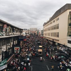 Crowd on road in city against sky