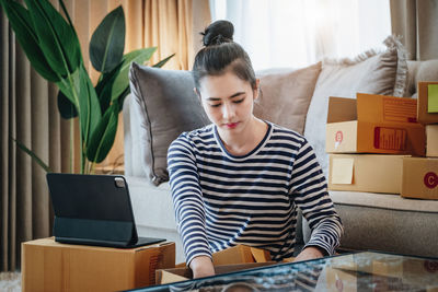 Side view of young woman sitting on sofa at home