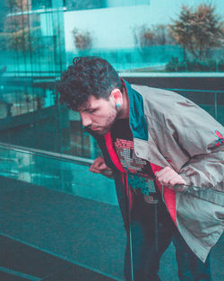 Portrait of young man looking through window