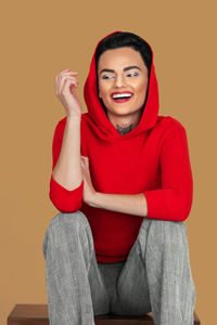 Portrait of young woman sitting against blue background