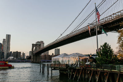 Sailboats moored on river by buildings against clear sky