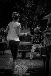 Rear view of people standing on bench in park