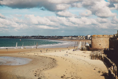 Scenic view of beach against cloudy sky in city