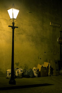 Illuminated street light against wall at night
