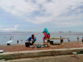 People working on beach against sky