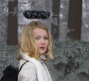 Young woman wearing costume wing and halo at forest during winter