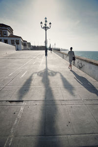 Rear view of man walking on footpath in city