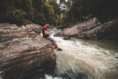 Man surfing on rock by river