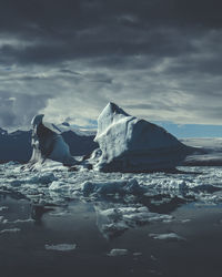 Ice floating on sea shore against sky