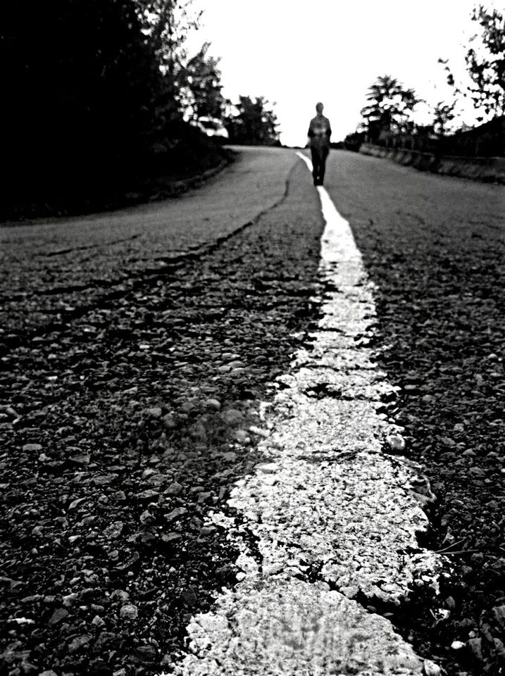 the way forward, road, diminishing perspective, walking, lifestyles, full length, vanishing point, transportation, leisure activity, asphalt, street, rear view, tree, surface level, clear sky, sunlight, dirt road, shadow