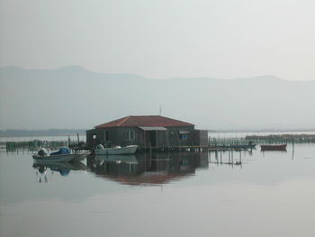 Boats moored by hut in river