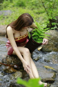 Midsection of woman with arms raised on rock