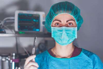 Portrait of female surgeon holding surgical tool at operating room