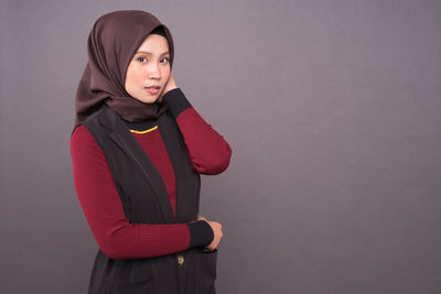 Portrait of young woman standing against red background