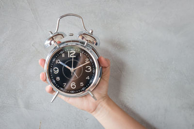 Close-up of human hand holding clock
