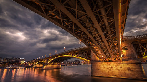 Low angle view of illuminated bridge against cloudy sky