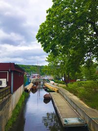 Canal amidst trees and buildings against sky
