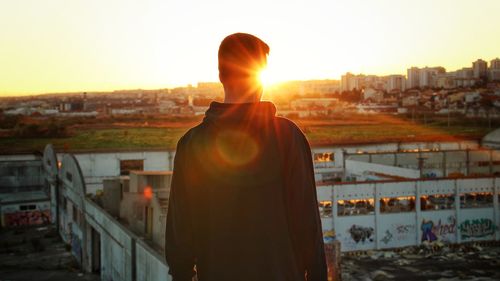 Rear view of man standing by cityscape against sky