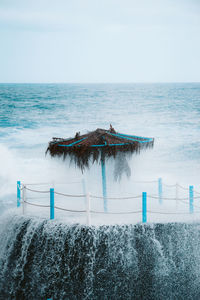 Powerful waves of sea crashing near straw umbrella and fence on stormy day on beach of la palma island in spain