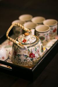 High angle view of teapot with cups on table