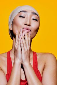 Close-up of young woman against yellow background