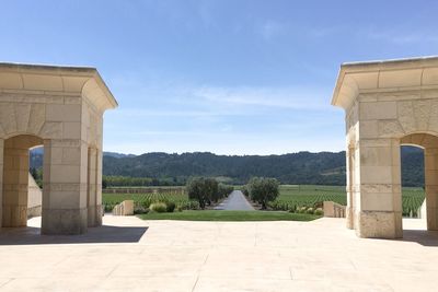 Built structure by formal garden against sky in sunny day