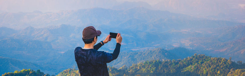 Rear view of person photographing on mountain