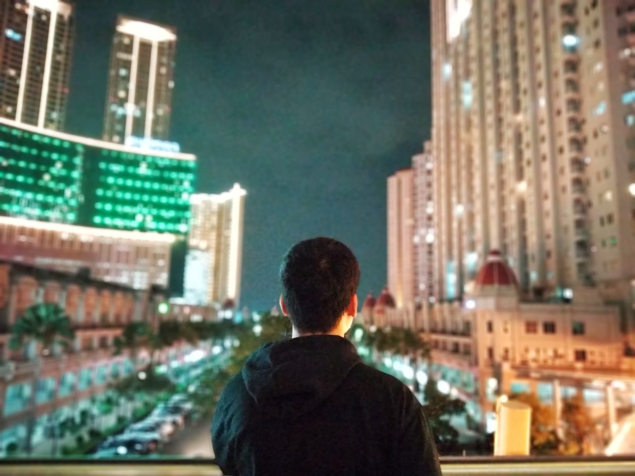 REAR VIEW OF MAN LOOKING AT CITYSCAPE