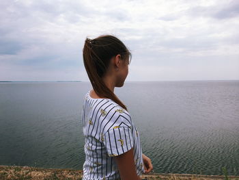 Side view of man looking at sea against sky