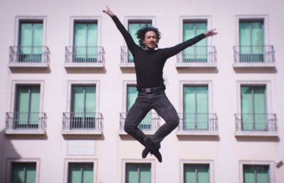 Full length of man jumping against building