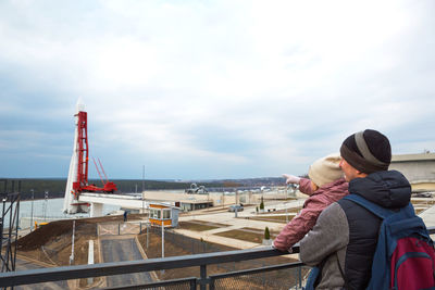 People standing on bridge against sky during winter