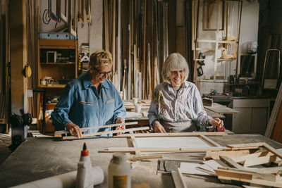 Smiling senior female entrepreneurs discussing while working at repair shop