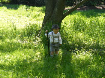 Little boy standing on grassy field in forest